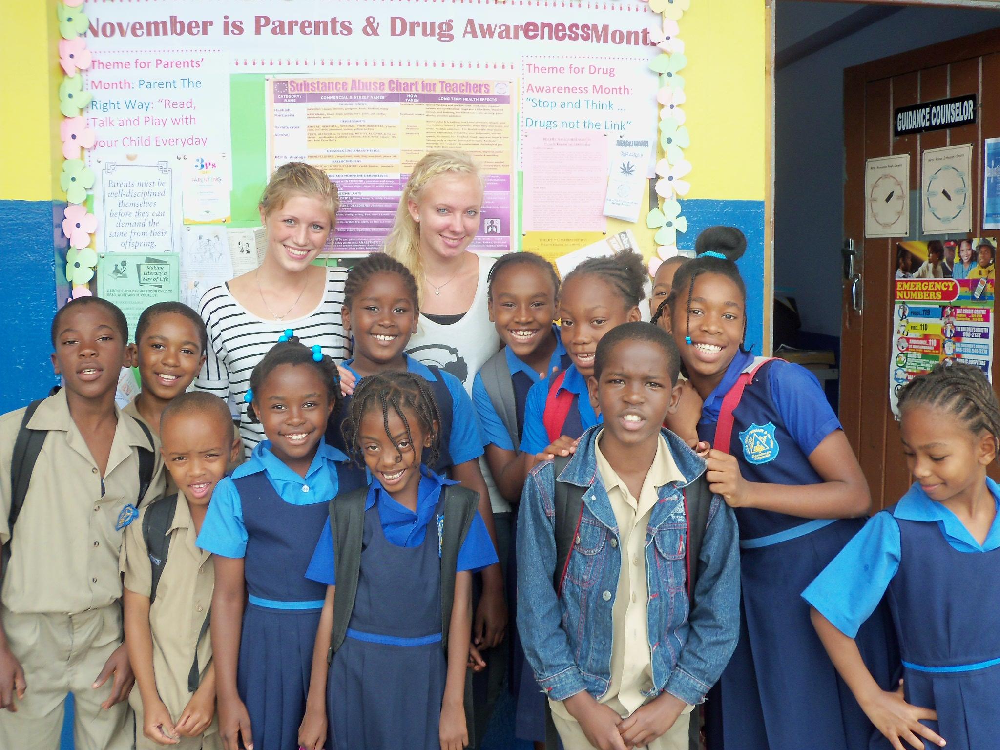 Teachers and their students pose outside the volunteer teaching placement in Jamaica Projects Abroad volunteers teaching in Jamaica pose with their students